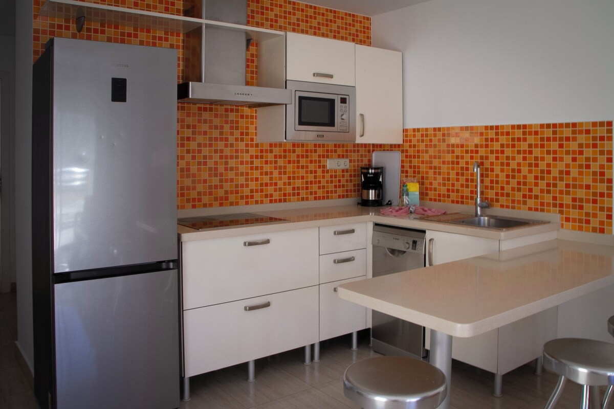 A compact kitchen with a refrigerator, microwave, coffee maker, and a small sink.
