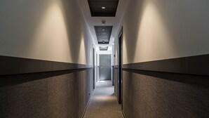 A narrow, well-lit hallway with a carpeted floor and walls featuring a dark and light panel design. - BYPILLOW San Mamés (Bilbao)