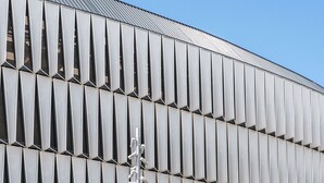 A modern building with a unique facade featuring a series of vertical panels. - BYPILLOW San Mamés (Bilbao)