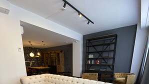 A modern living room with a white tufted sofa, a wooden coffee table, and a bookshelf. - BYPILLOW San Mamés (Bilbao)