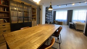 A spacious room with a large wooden dining table, bookshelves, and a cozy seating area with a sofa and armchairs. - BYPILLOW San Mamés (Bilbao)