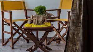 Uma área de refeições com cadeiras de madeira e uma mesa, uma decoração de barco à vela pendurado e uma cortina parcialmente visível.