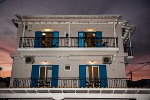 A two-story building with balconies, air conditioning units, and outdoor seating. - Summer Bed Nydri (Lefkada)