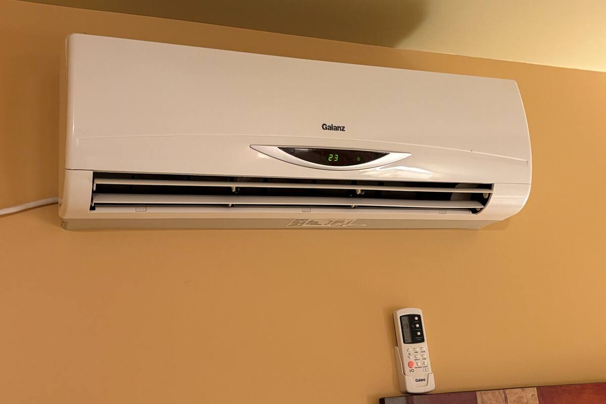 A white Galanz air conditioner mounted on a wall with a remote control placed below it.