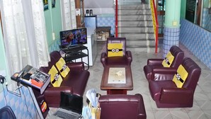 Un vestíbulo con mostrador de recepción, televisión y asientos con cojines temáticos de Minions.