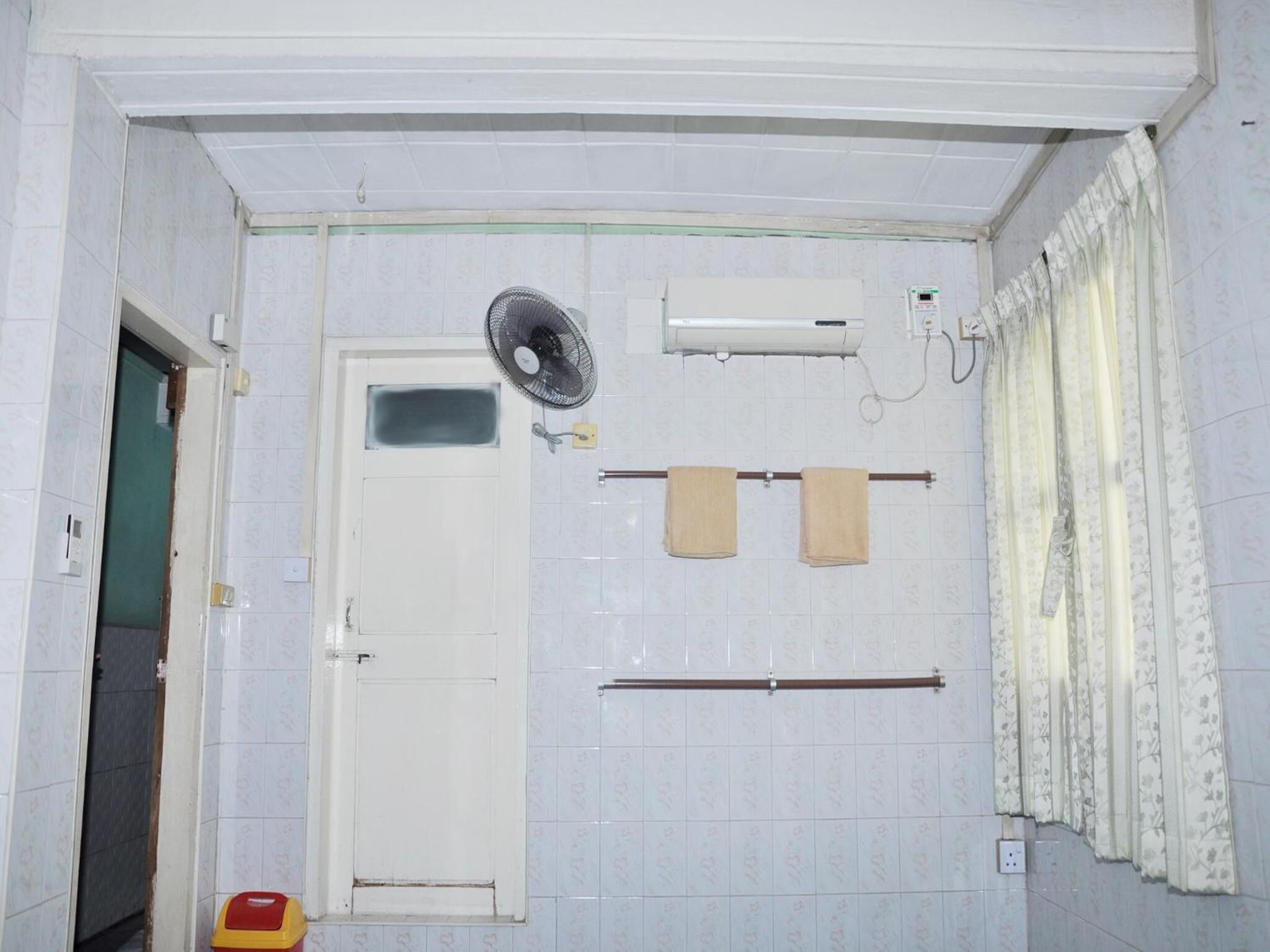 Une salle de bain avec une porte blanche, un ventilateur, un porte-serviettes, un porte-rouleau de papier toilette et un rideau de douche.