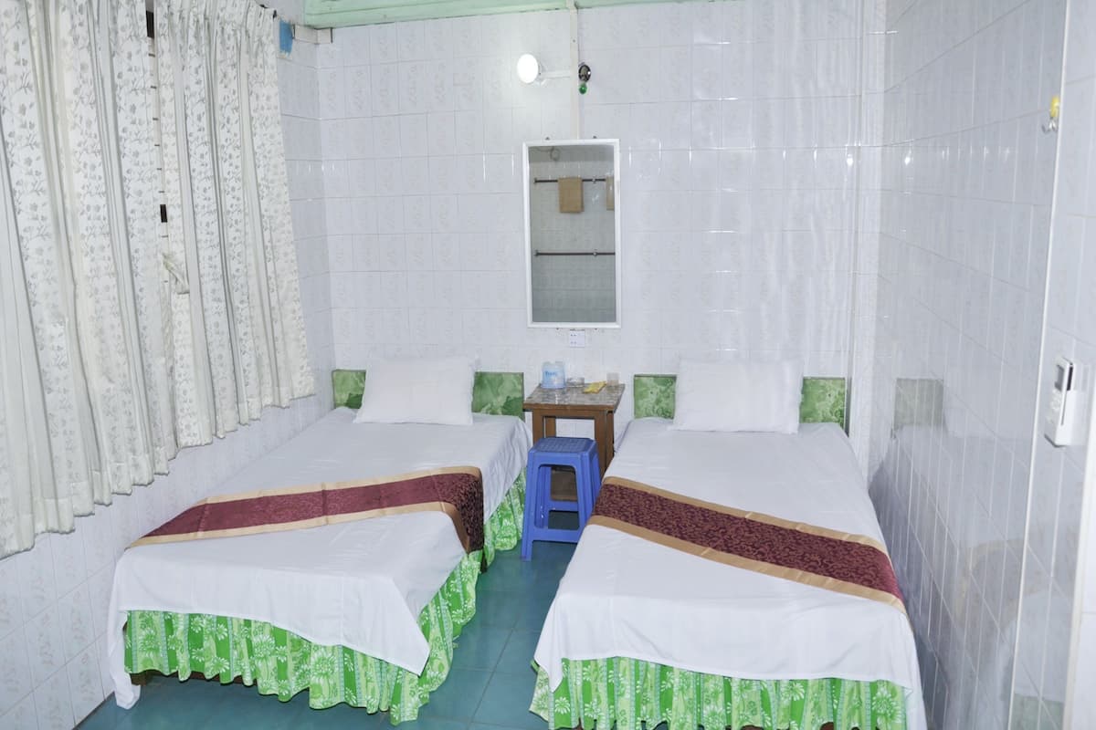 A room with two beds, a small table, and a ceiling fan.