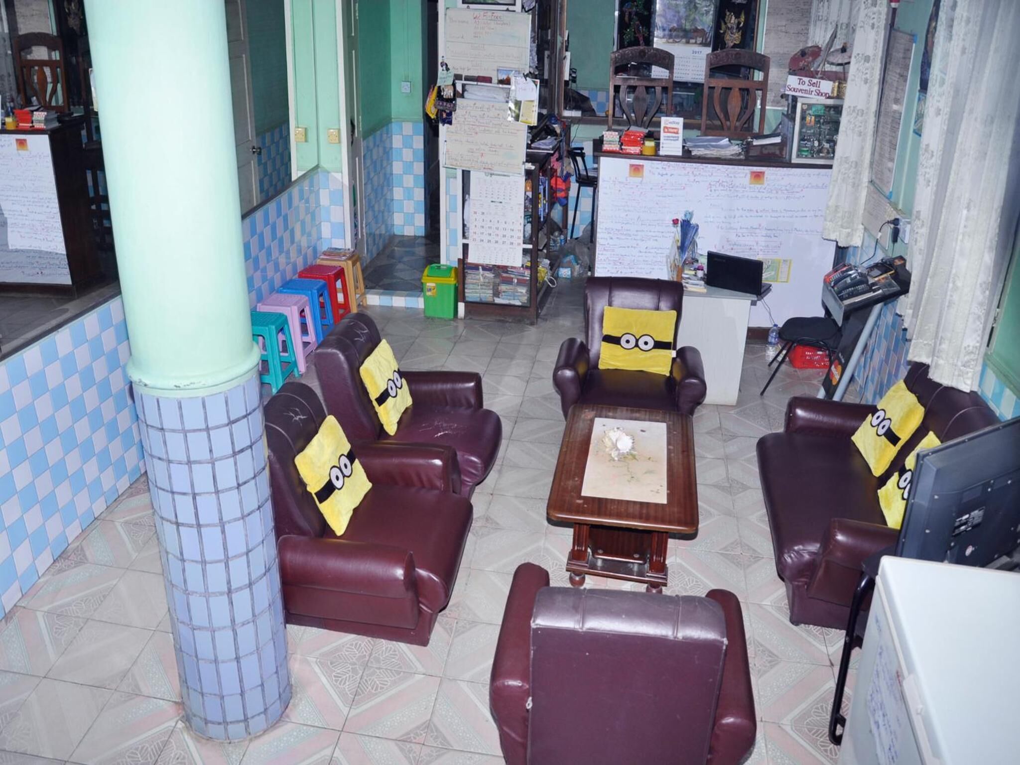 A lobby with leather sofas and armchairs, a small wooden table, and a trash bin.