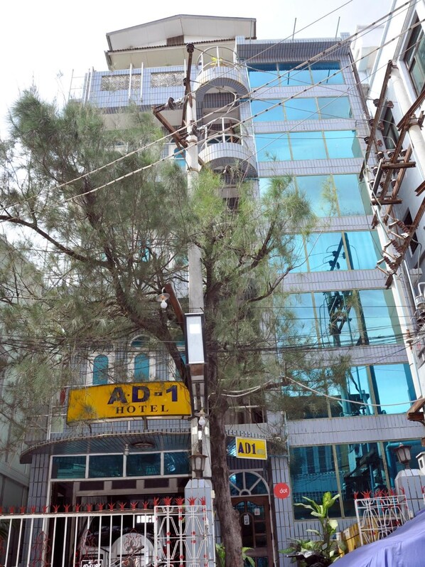 Un edificio de varios pisos con un letrero amarillo grande que dice "AD-1 HOTEL" y un letrero más pequeño con el mismo nombre en la planta baja.
