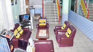 Un vestíbulo con asientos de cuero, un escritorio con computadora y una escalera con barandas rojas.