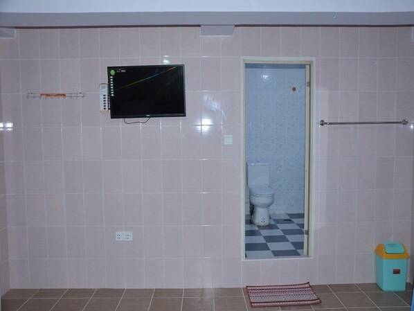 A bathroom with a toilet, a sink, a mirror, and a television mounted on the wall.