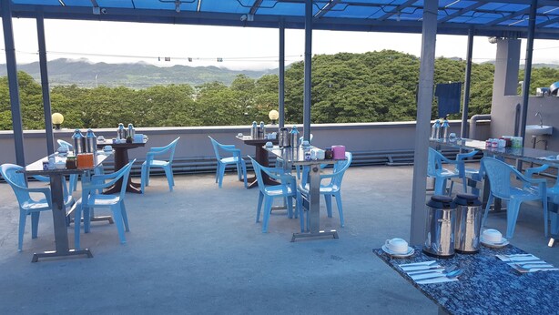An outdoor dining area with blue chairs and tables, overlooking a mountainous landscape. - Red Dragon Hotel Hsipaw (Hsipaw)