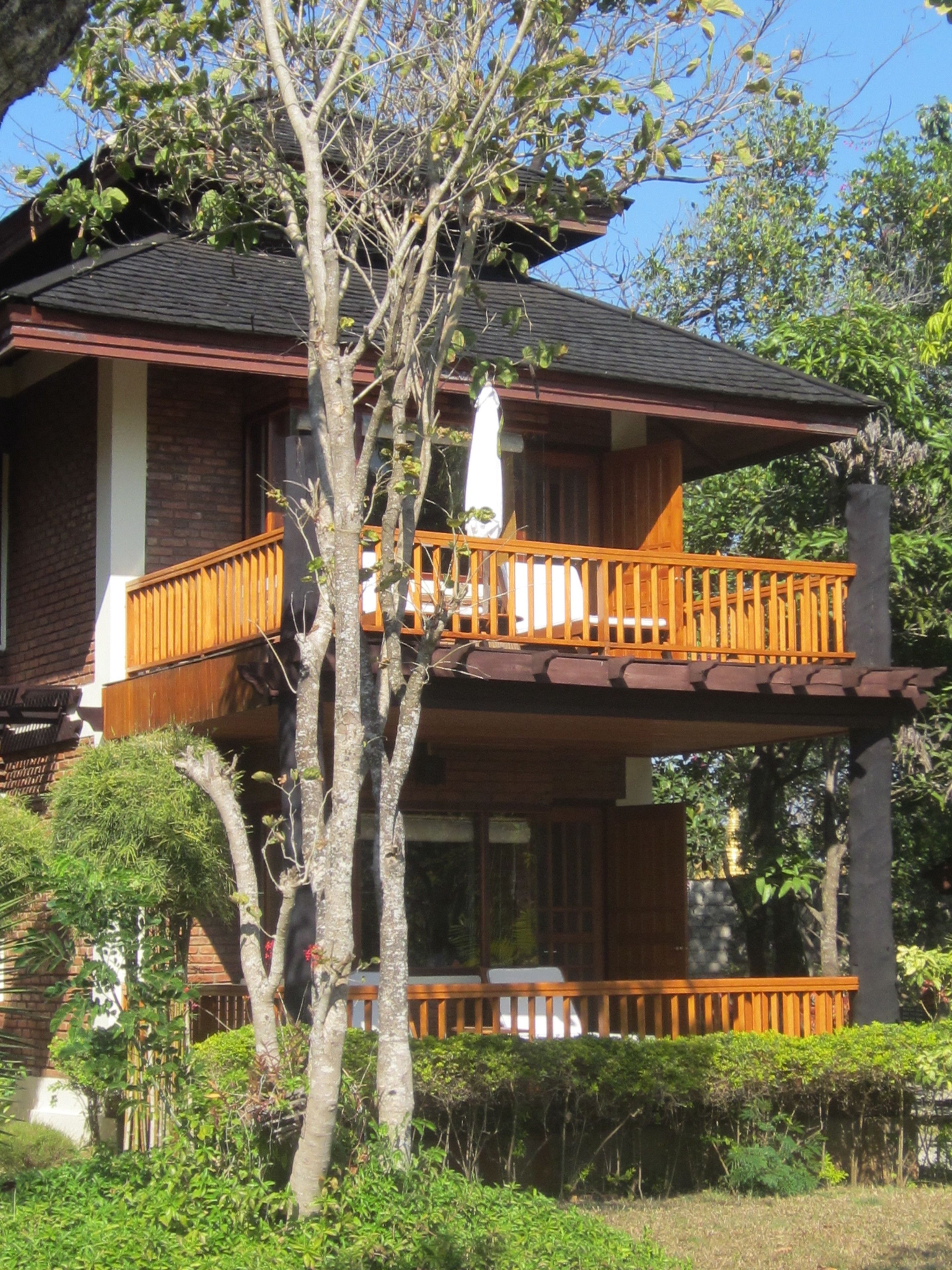 A two-story house with a balcony and a tree in front.