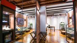 Un interior moderno con paredes de ladrillo visto, vigas de madera y una variedad de espacios para sentarse, incluyendo un sofá y un banco.