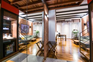 A modern interior with exposed brick walls, wooden beams, and a mix of seating areas including a sofa and a bench.