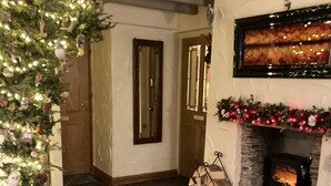 Un salon chaleureux avec une cheminée, un sapin de Noël et un tapis à motifs.