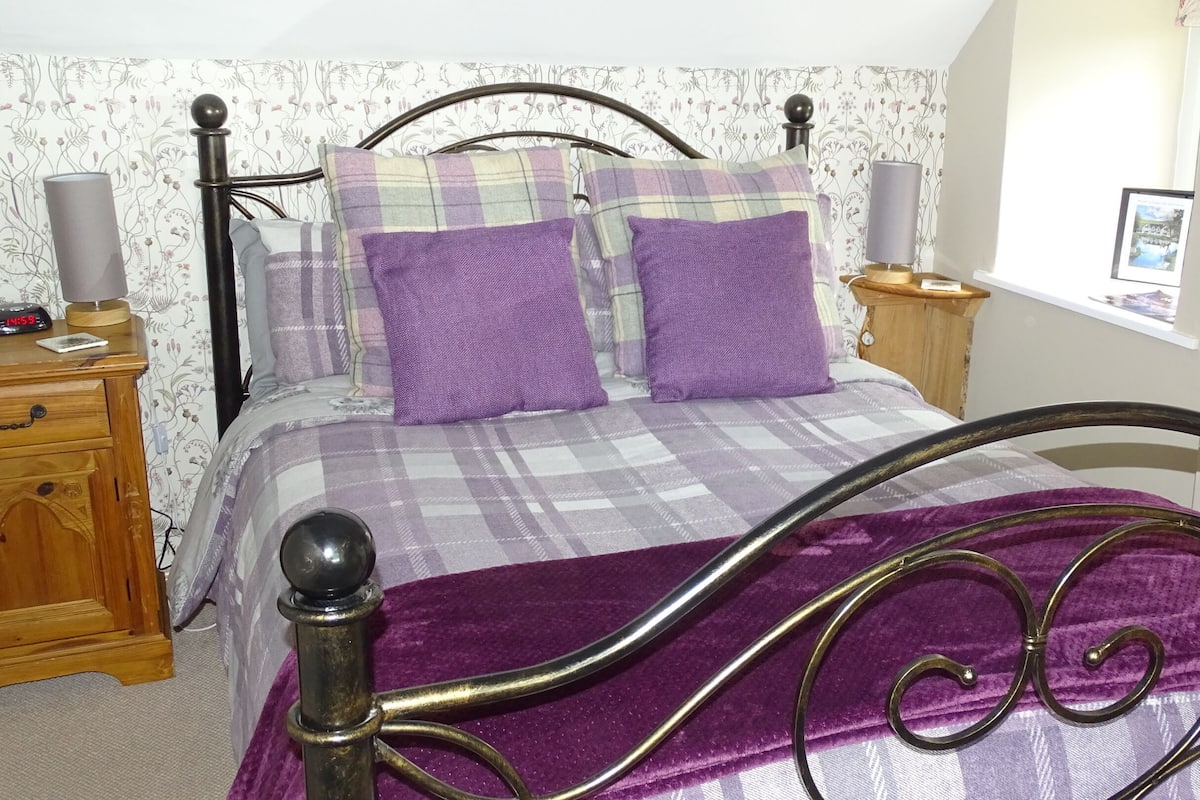 Une chambre à coucher avec un lit, une table de chevet, une lampe et une commode.