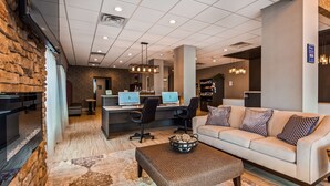 Een moderne lobby met een accentmuur van steen, een receptiebalie met computers, een bank met gestreepte kussens en een salontafel met decoratieve objecten.