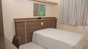 Una cama individual con cabecera de madera, una mesita de noche pequeña y una silla.