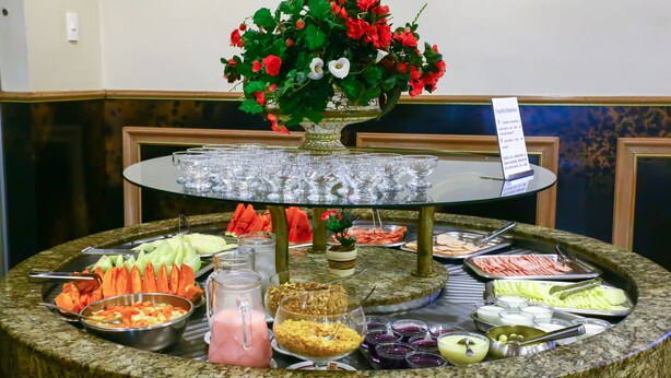 Una mesa de buffet con diversos alimentos, un jarrón decorativo y un letrero.