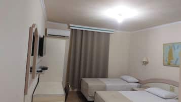 A hotel room with two beds, a desk, a television, and a window with curtains.