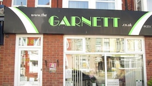 A storefront with a sign reading "www.the GARNETT.co.uk" and a phone number "01253 3".