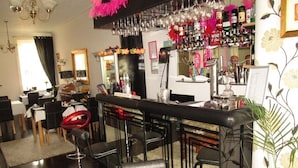 A bar area with a counter, chairs, and a variety of bottles and glasses.