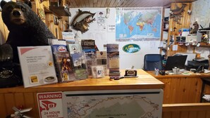 A reception desk with a bear statue, a map of Algonquin Provincial Park, and various informational posters. - All Star Resort (South Algonquin)