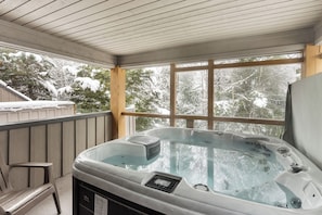 Ein Whirlpool in einem überdachten Außenbereich mit Blick auf schneebedeckte Bäume.