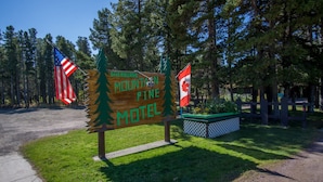 A wooden sign for the Sherburne Mountain Pine Motel with two flags, one American and one Canadian.