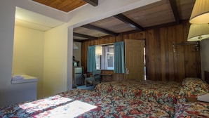 A bedroom with a bed, a chair, a desk, and a window with curtains.