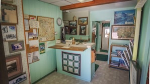 A small, cozy room with a wooden desk, a map on the wall, and various framed pictures and documents.