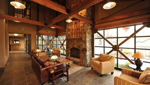 A spacious lobby with a stone fireplace, leather sofas, and large windows offering views of the outside.
