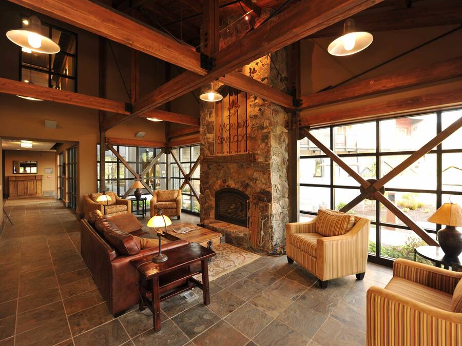A spacious lobby with a stone fireplace, leather sofas, and large windows offering views of the outside.