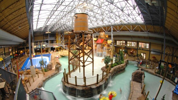 An indoor water park with a large central water feature, multiple slides, and a pool area.