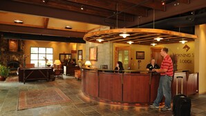 A reception area with a wooden reception desk, a stone fireplace, and a large window.