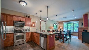A modern kitchen with wooden cabinets, stainless steel appliances, and pendant lighting.