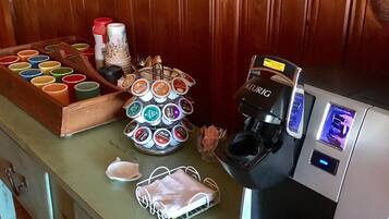 A coffee machine with multiple coffee pods, a tray of colorful cups, and a white basket on a counter.