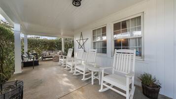 A covered porch with white rocking chairs and a star decoration.
