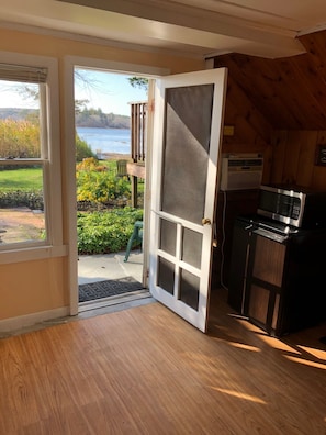 A wooden interior with a sliding glass door leading to a deck overlooking a body of water.