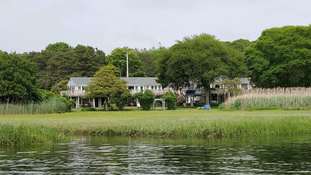 A lakeside property with a large building featuring multiple rooms and a covered outdoor area. - Spring Garden Inn (East Sandwich)