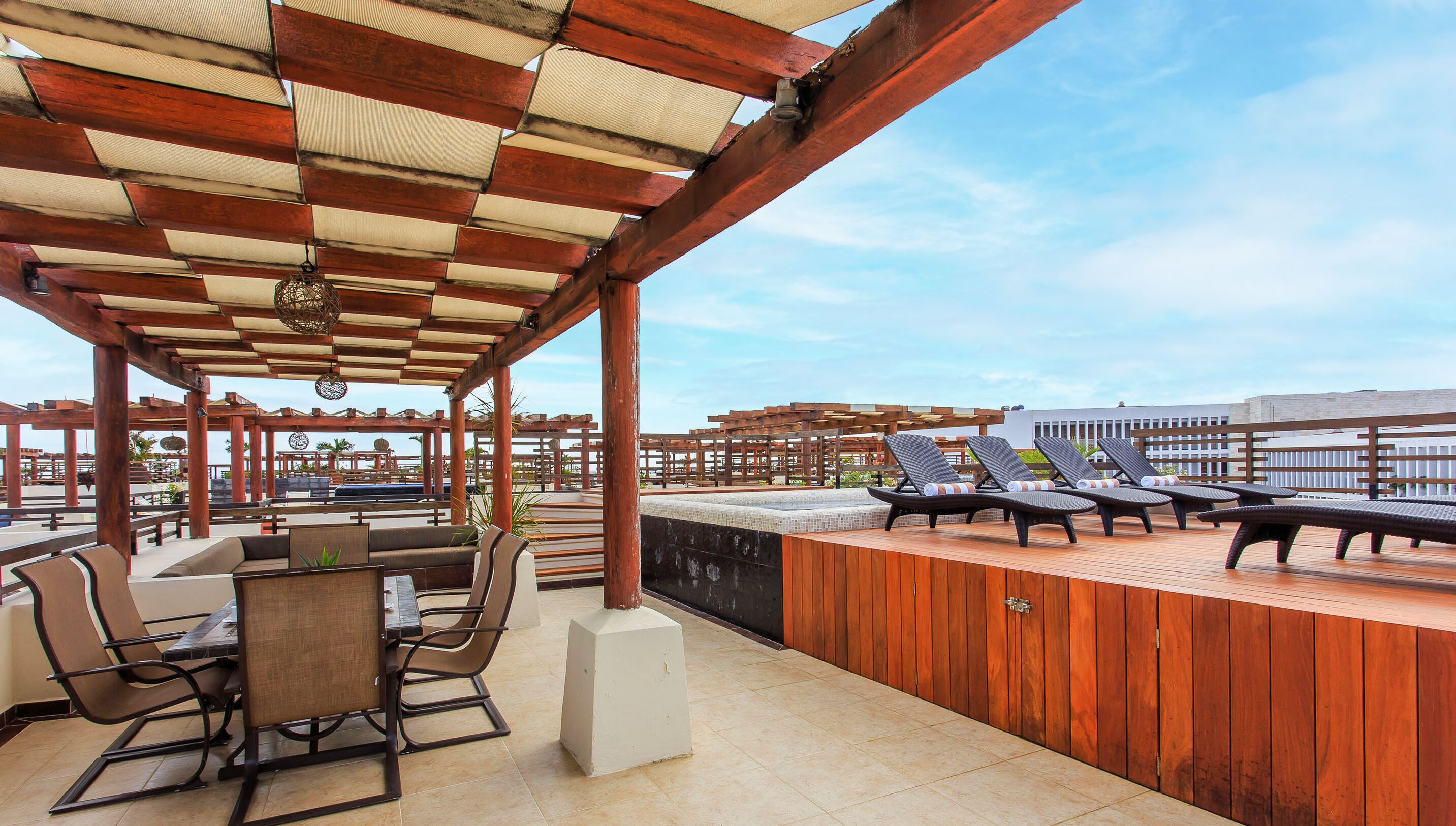 Une terrasse extérieure avec des meubles en bois, une table et des chaises longues.