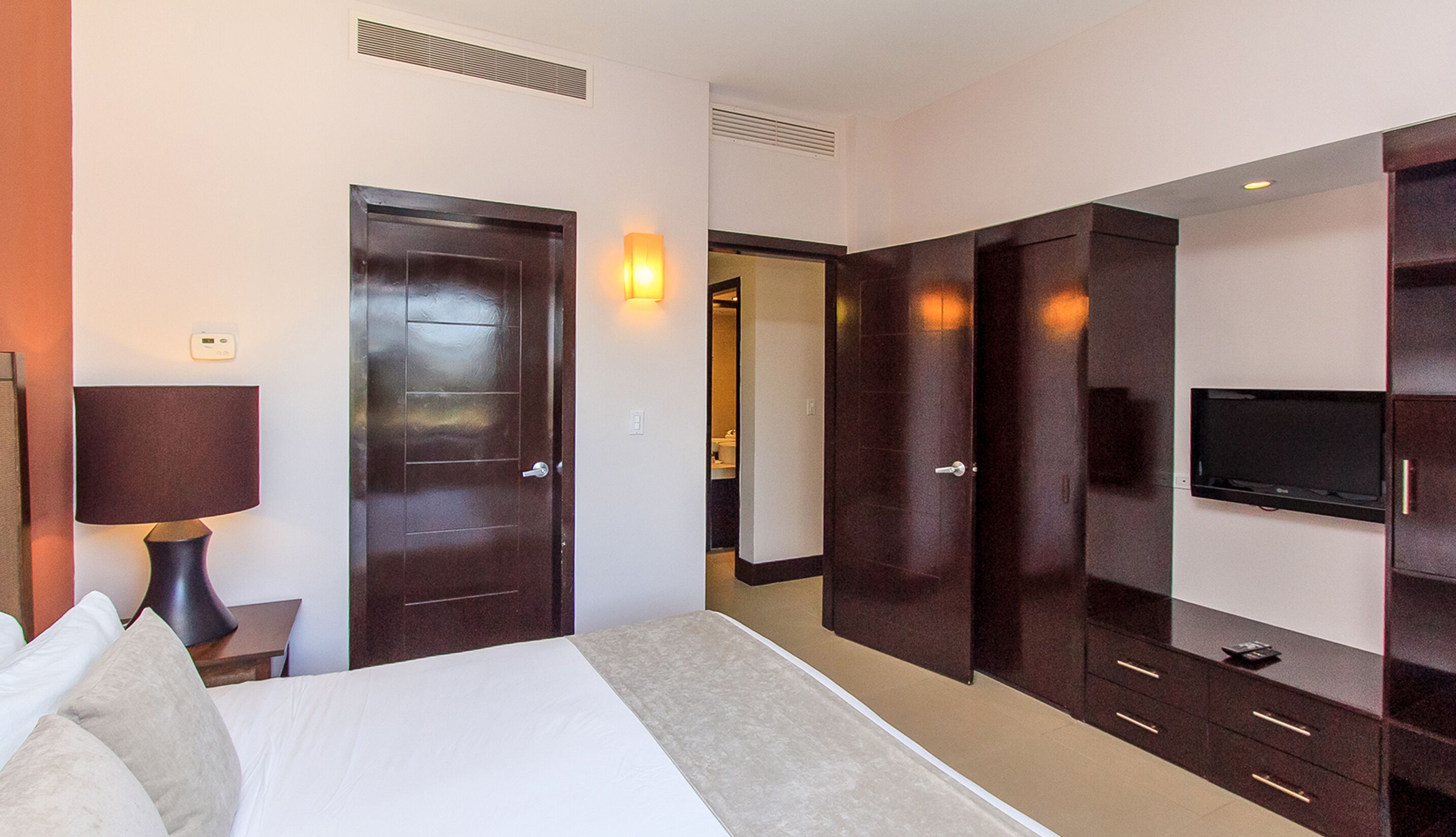 Une chambre d’hôtel comprenant un lit, une lampe de chevet, une armoire et un téléviseur.