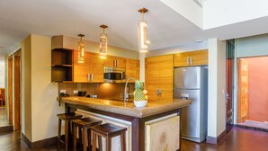 Una cocina moderna con armarios de madera, electrodomésticos de acero inoxidable y una isla central con taburetes.