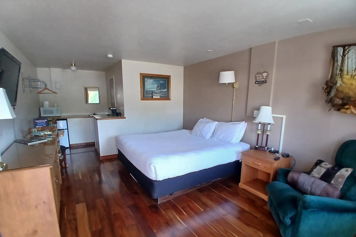 Une chambre d’hôtel comprenant un lit, des tables de chevet, un bureau, une chaise et un téléviseur.