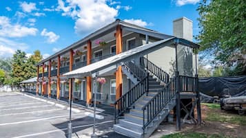 Een motel met een overdekte buitenzitplaats, een trap naar een tweede verdieping en een parkeerplaats.