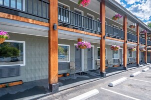 A hotel with a covered outdoor area, multiple balconies, and hanging flower baskets.