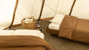 Un interior acogedor con dos camas, una cesta de mimbre y una pequeña mesa con una vela.