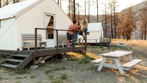 Una carpa con una terraza de madera, un banco y una mesa de picnic.