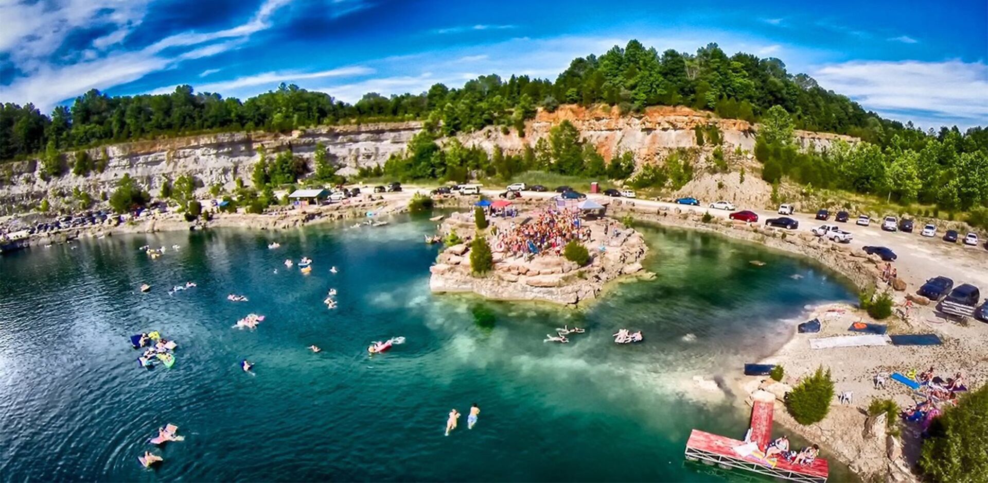 Un resort sul lago con un'isola centrale, barche e un'area di parcheggio.
